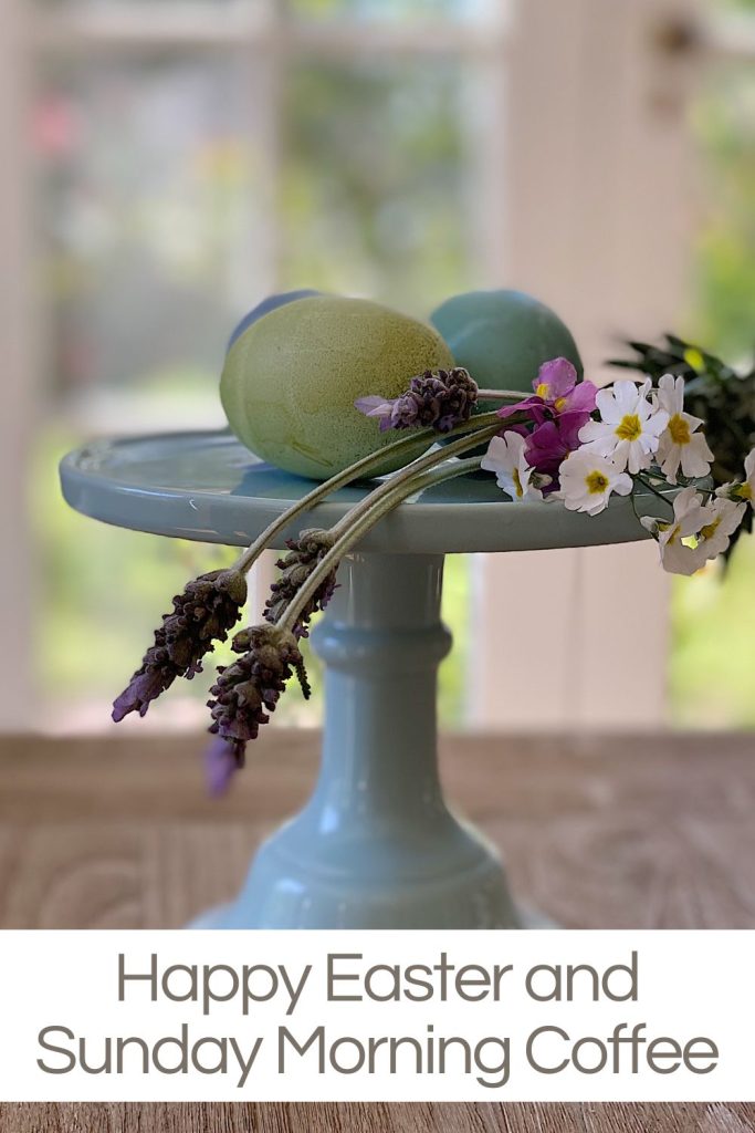 a blue cake plate with three colored Easter eggs and some fresh flowers on top.