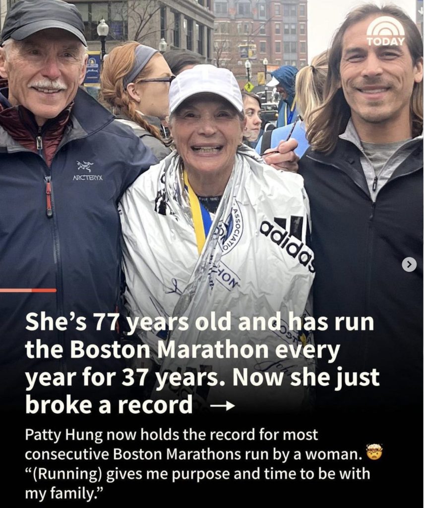 Smiling woman wrapped in mylar blanket after finishing her 37th Boston Marathon. She is surrounded by her husband and son