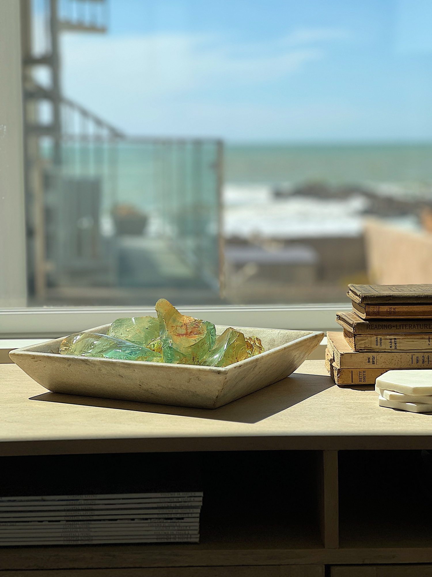 Old vintage decor books and a vintage marble container filled with old glass from a windshield factory next to a new gold lamp.
