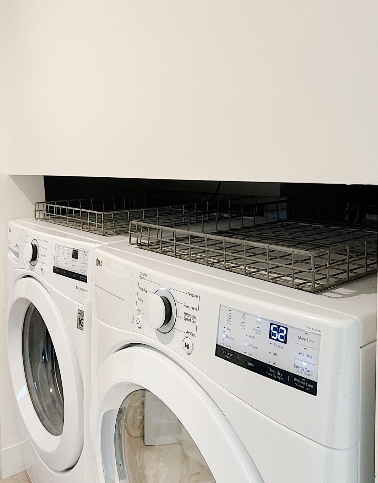 Two wire baskets sitting on top of a washer and dryer.