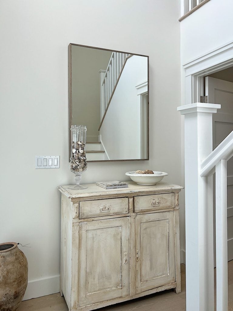 the entry was of our beach house with a vintage white cabinet, an apothecary jar filled with shells, an ironstone bowl and a Pottery Barn mirror.