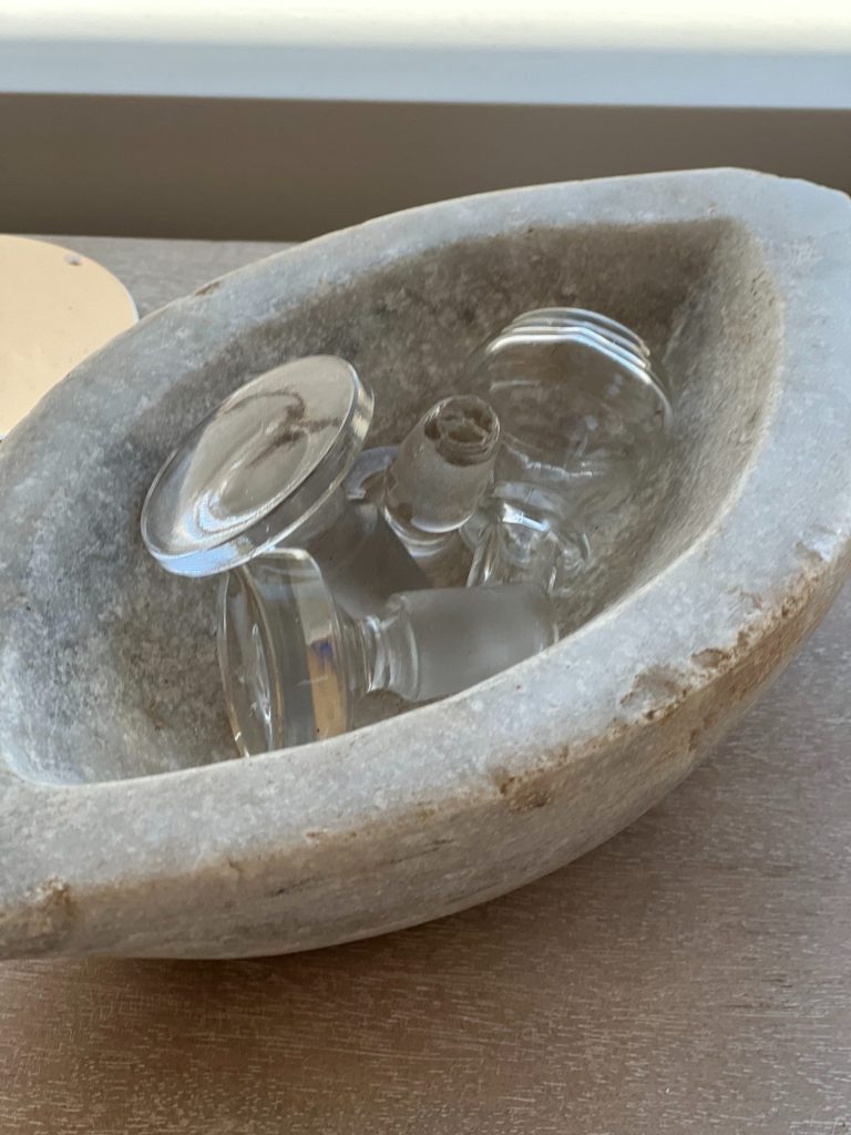 A marble vintage bowl filled with vintage glass stoppers.