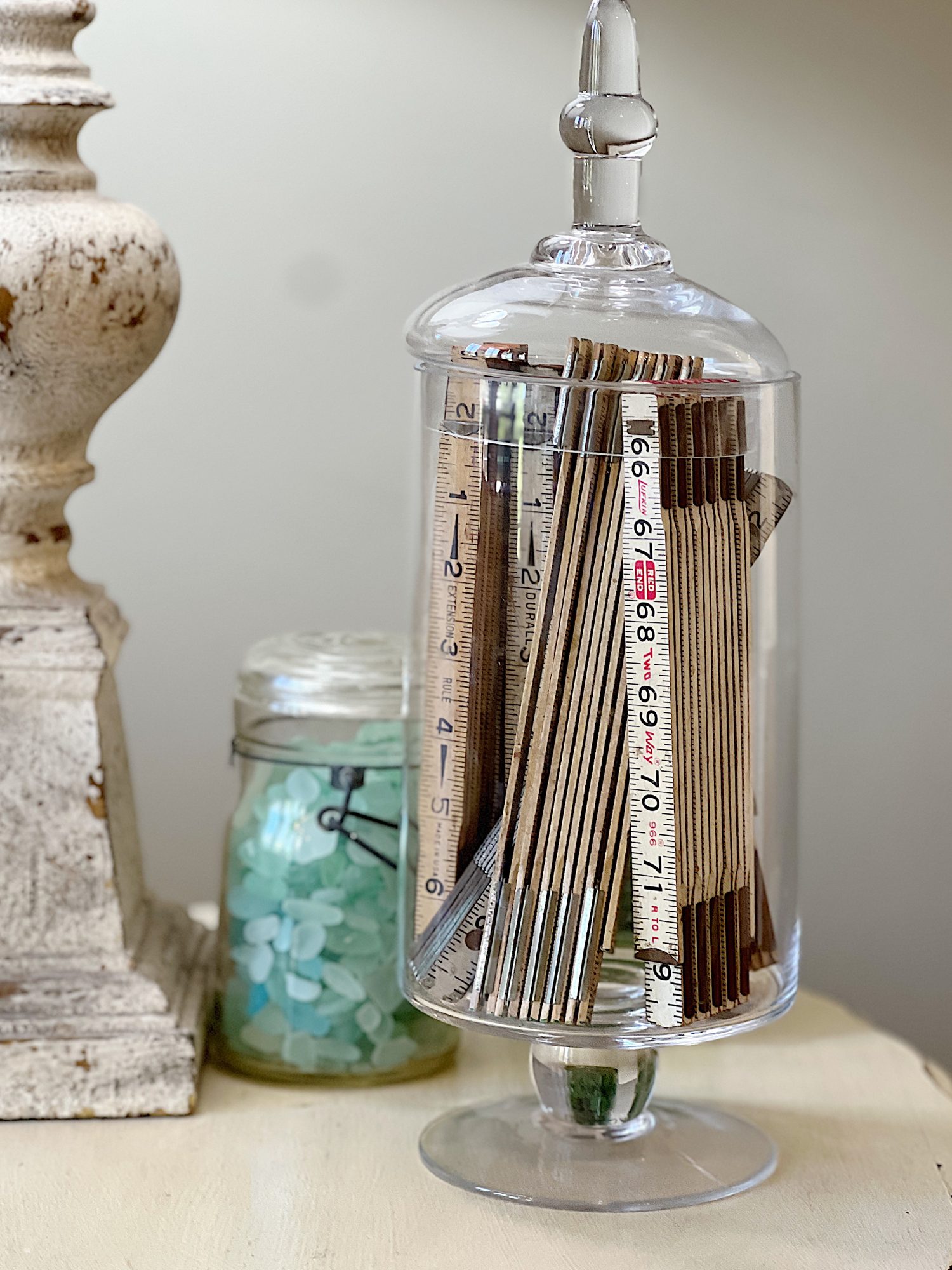 Glass apothecary glass jar filled with vintage measuring tapes.