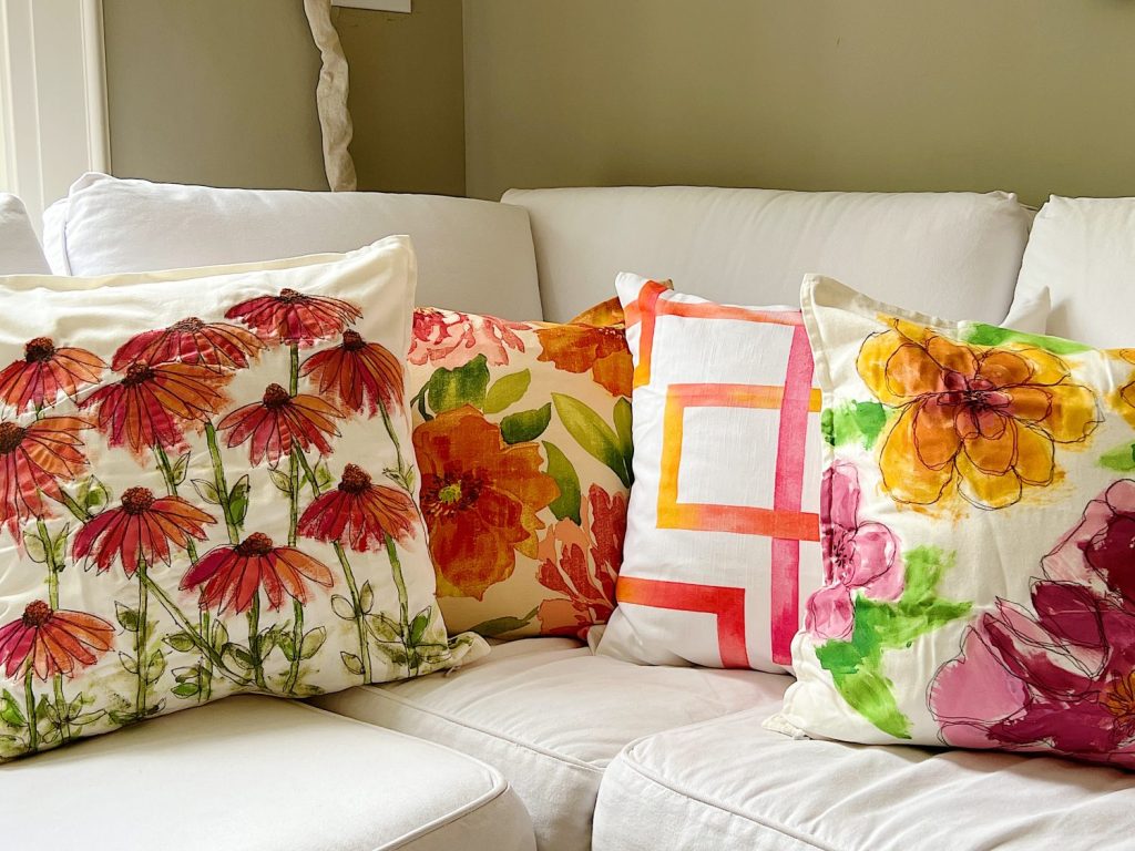 Orange printed pillows on a white couch.