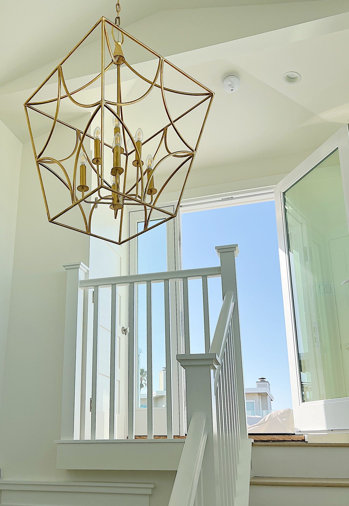 A large brass pendant hanging above a third-floor staircase.