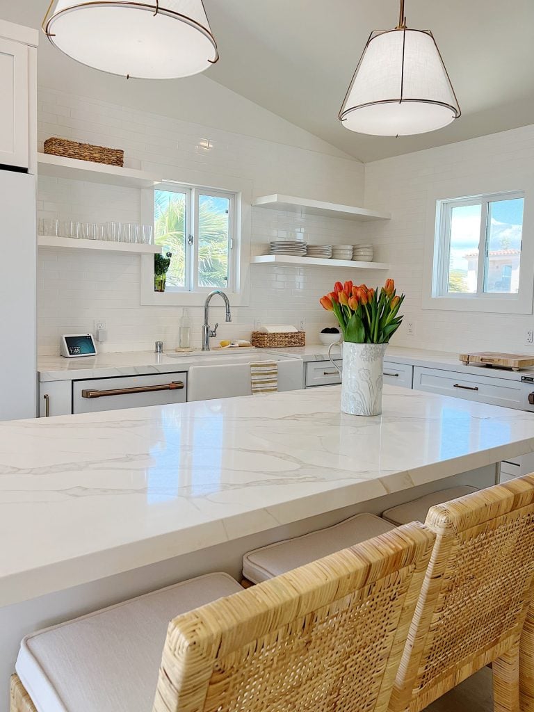 The finished beach house kitcehn with white cabinets, countertops, appliances, and an island.