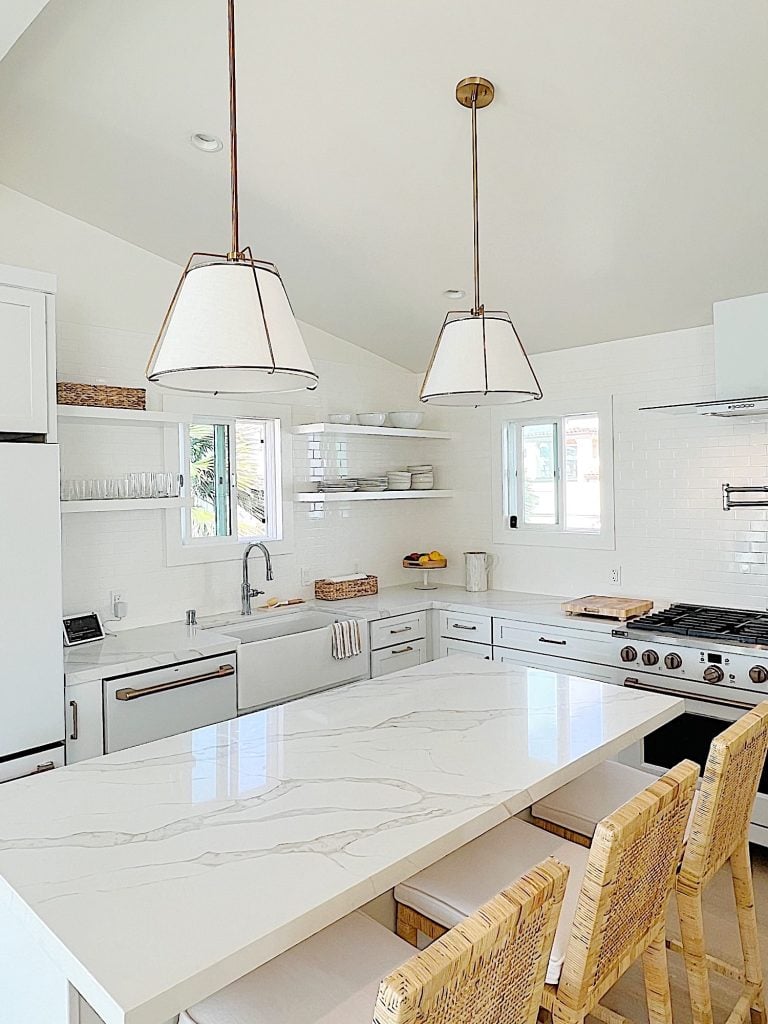 The finished beach house kitcehn with white cabinets, countertops, appliances, and an island.