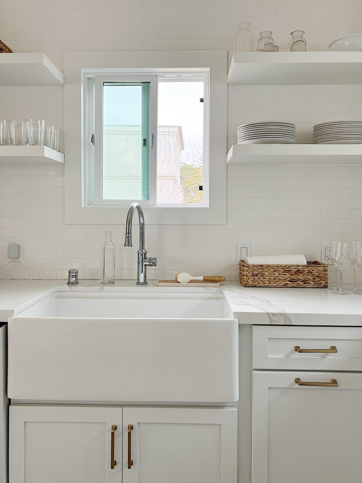 The finished beach house kitcehn with white cabinets, countertops, appliances, and an island.