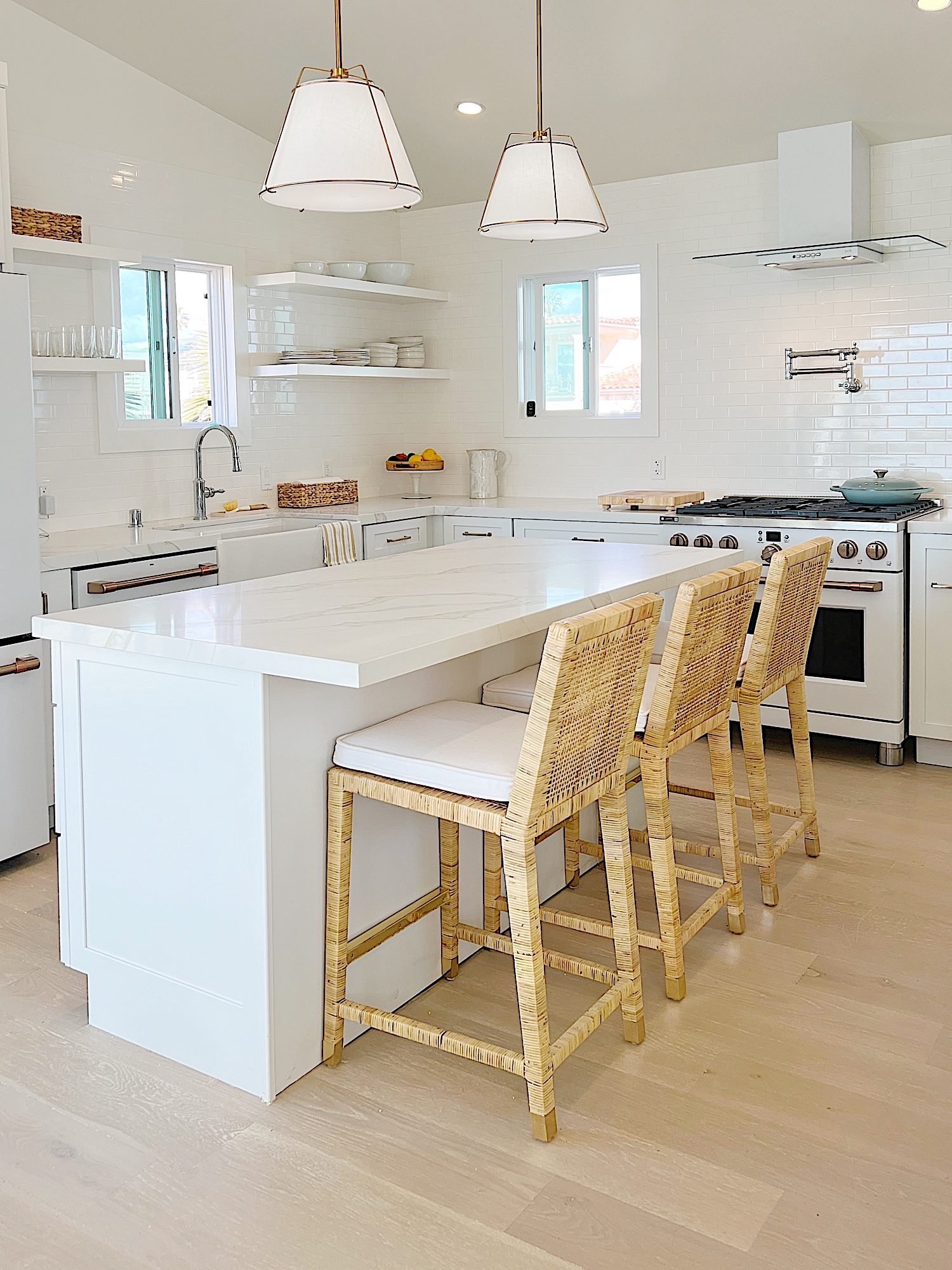 The finished beach house kitcehn with white cabinets, countertops, appliances, and an island.
