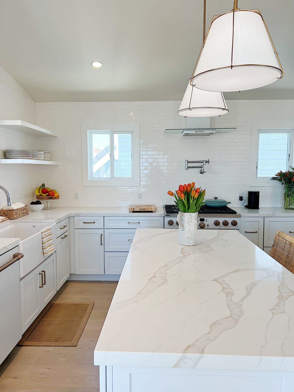 The finished beach house kitcehn with white cabinets, countertops, appliances, and an island.