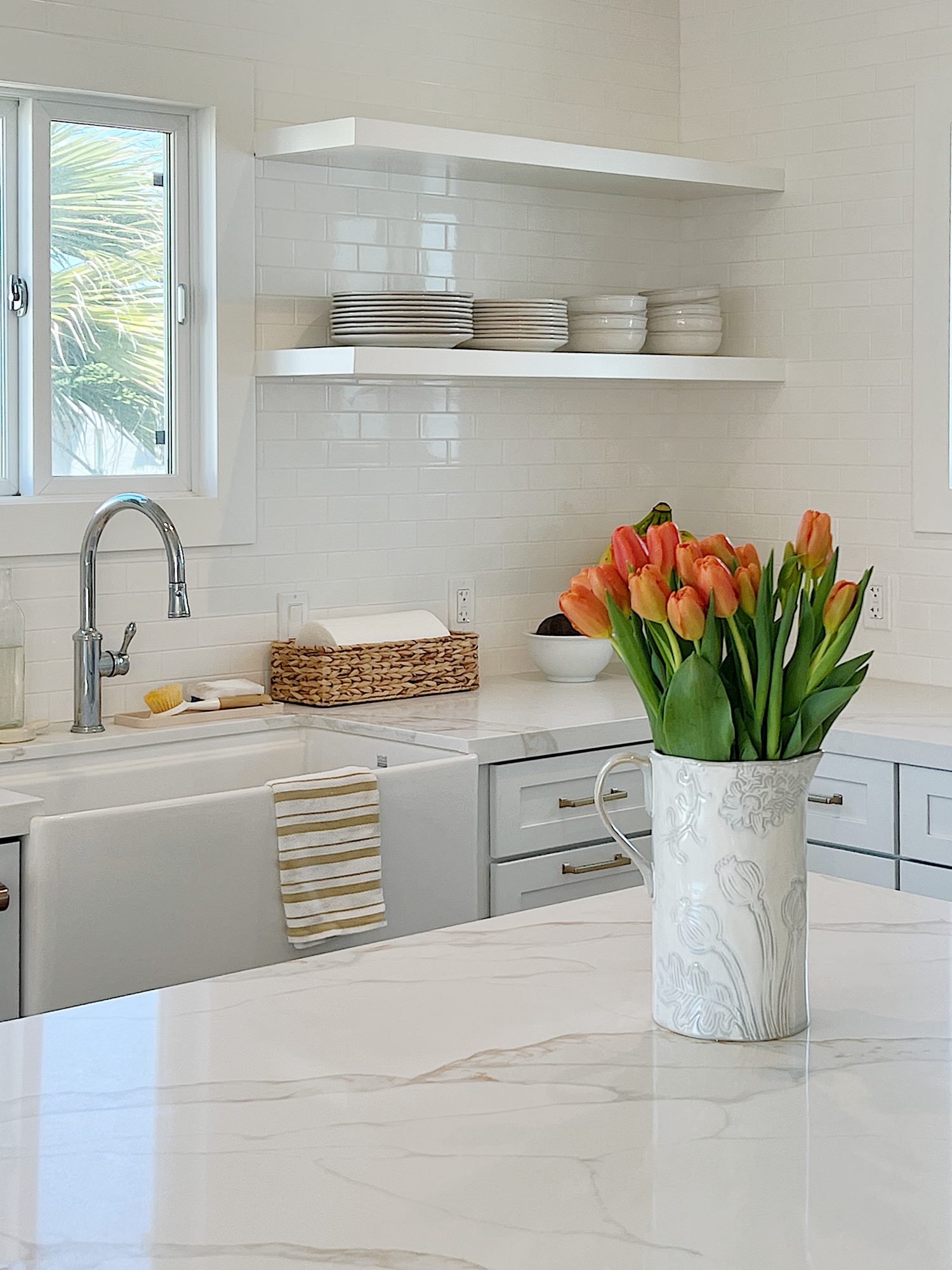 The finished beach house kitcehn with white cabinets, countertops, appliances, and an island.
