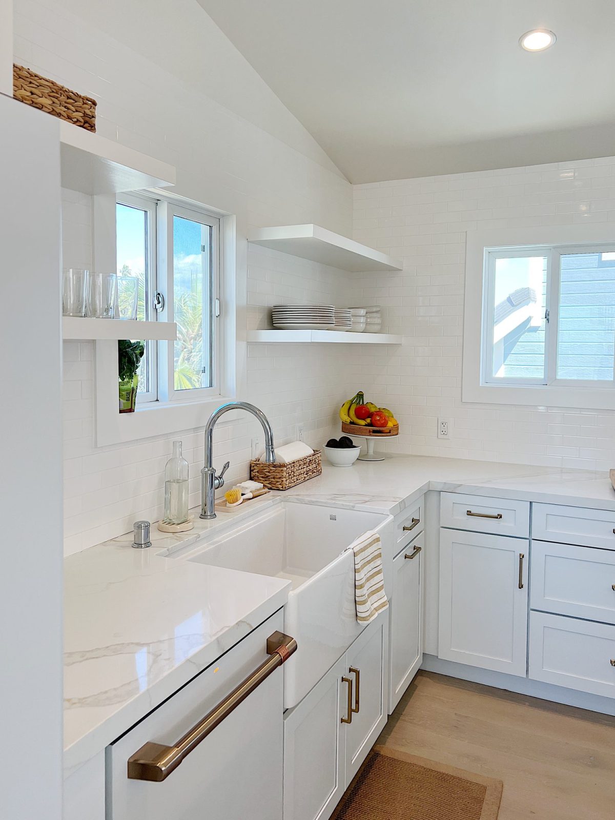 The finished beach house kitcehn with white cabinets, countertops, appliances, and an island.