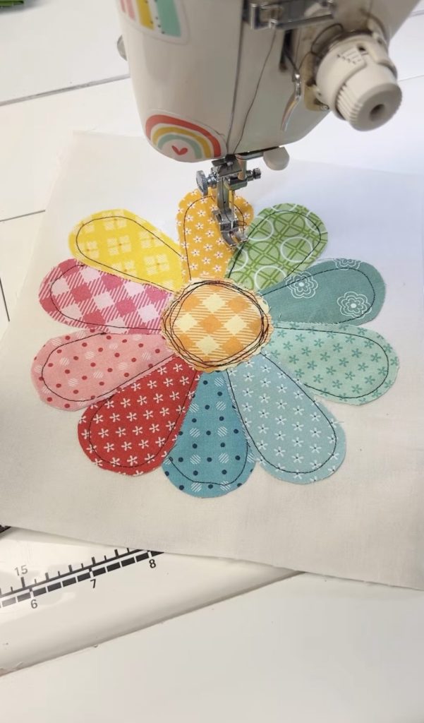 A sewing machine project of a flower with each petal in a rainbow of different colored and patterned fabric. 