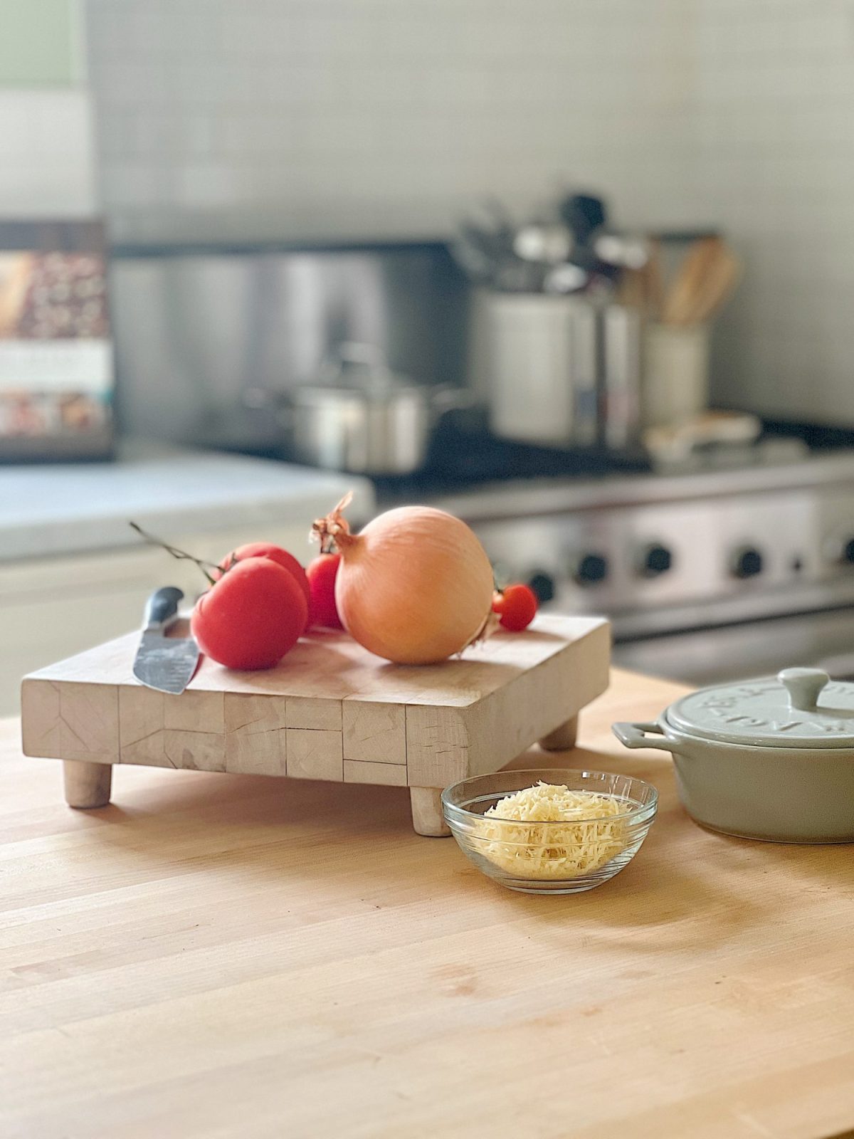 A white farmhouse kitchen with white shaker cabinets. honed marble countertops, an island with a butcher block top, and lots of farmhouse kitchen decor items.