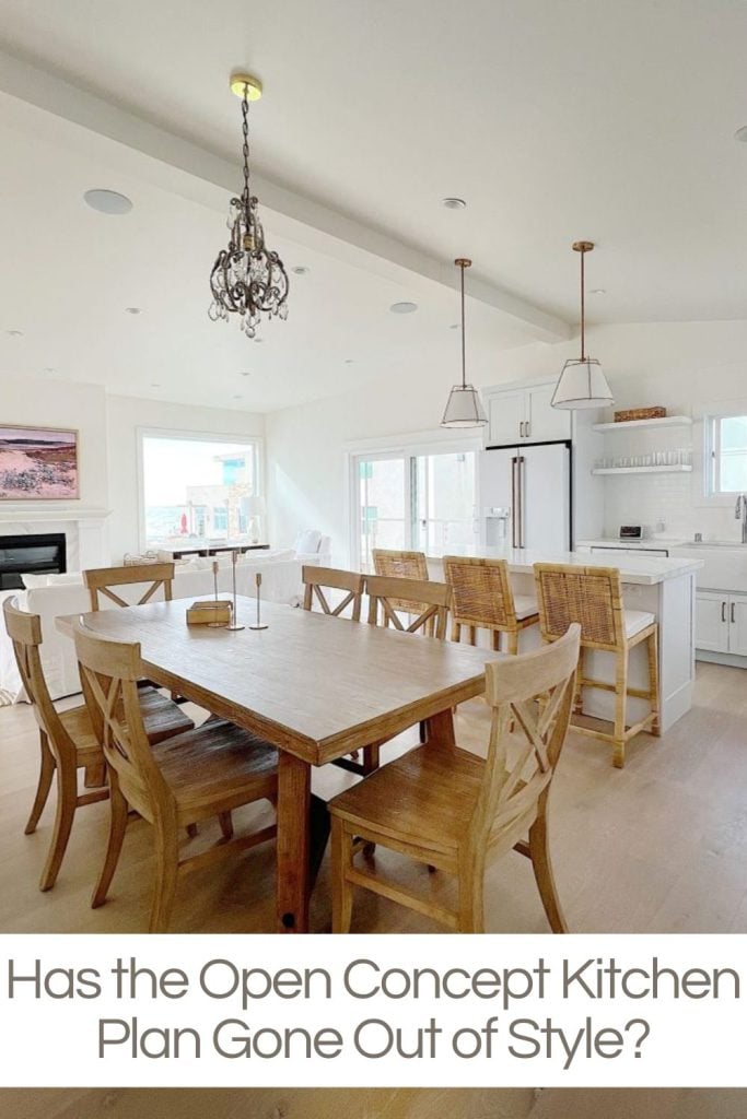 The open kitchen floor plan at our beach house wit a table, island, white cabinets and a living room.