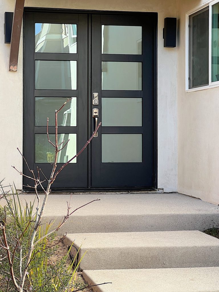 The modern black front door made from fiberglass at the beach house.