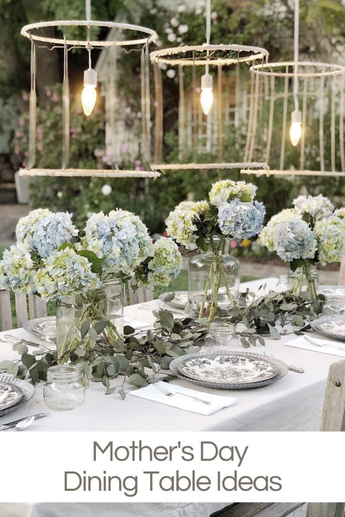 A table with hanging vintage chandeliers, fresh hydrangea centerpieces and black and white chinw.