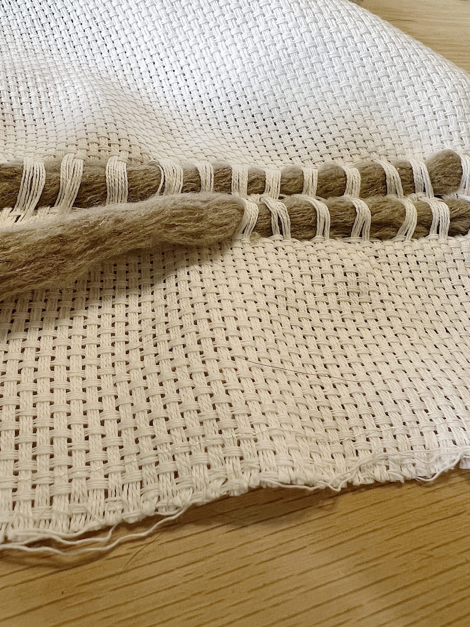 Handmade monk cloth pillow with yarn being constructed.