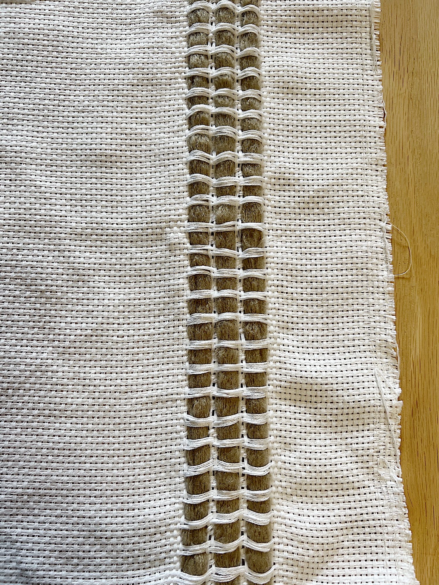 Handmade monk cloth pillow with yarn being constructed.