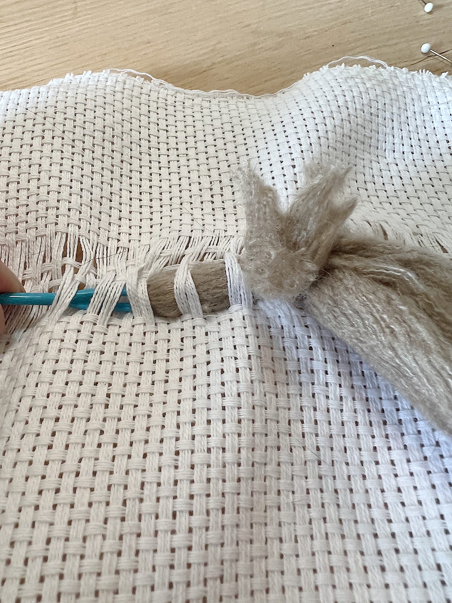 Handmade monk cloth pillow with yarn being constructed.