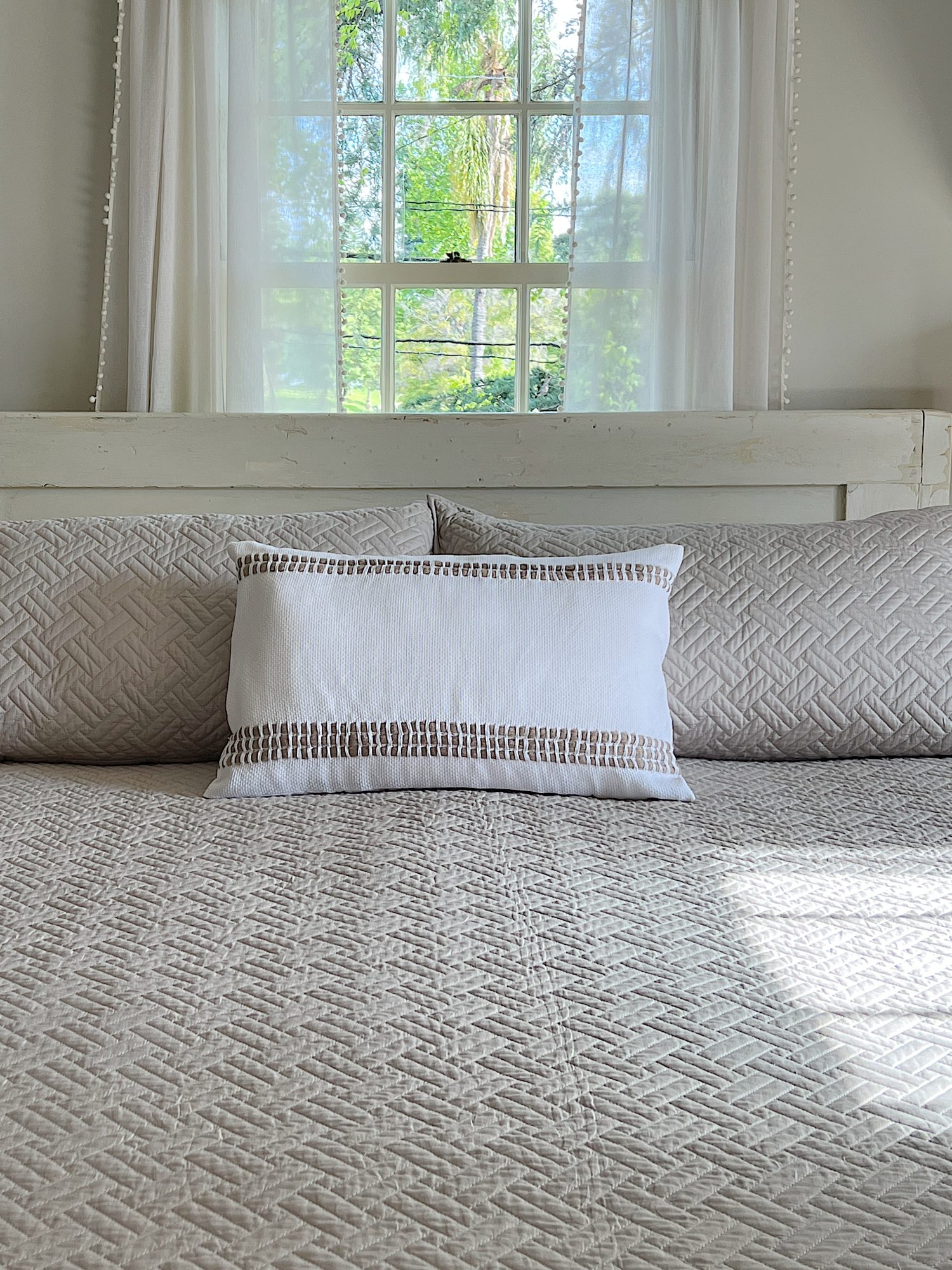 Handmade monk cloth pillow with yarn sitting on top of a bed