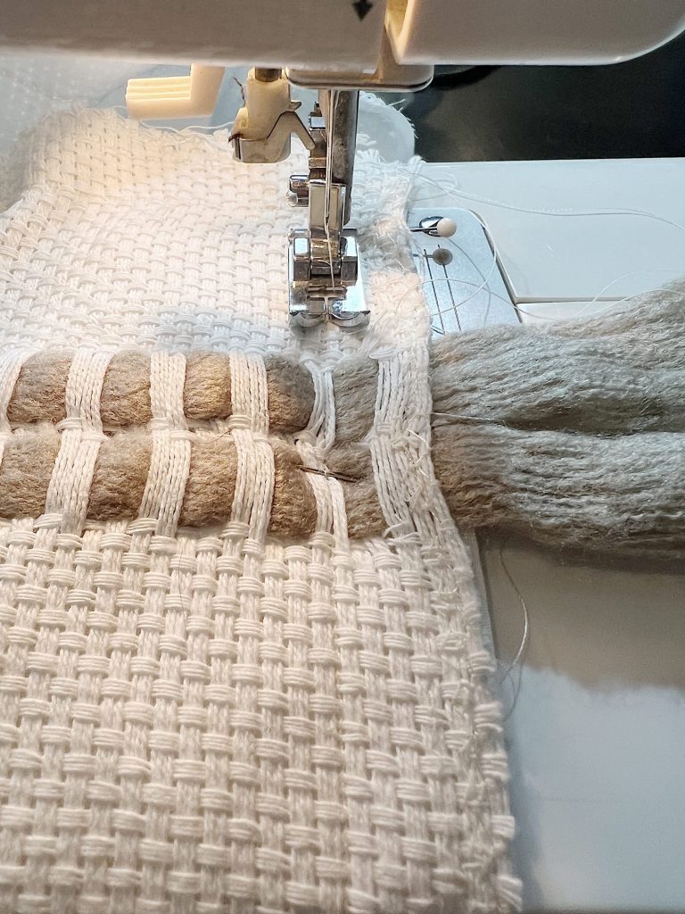 Handmade monk cloth pillow with yarn being constructed.