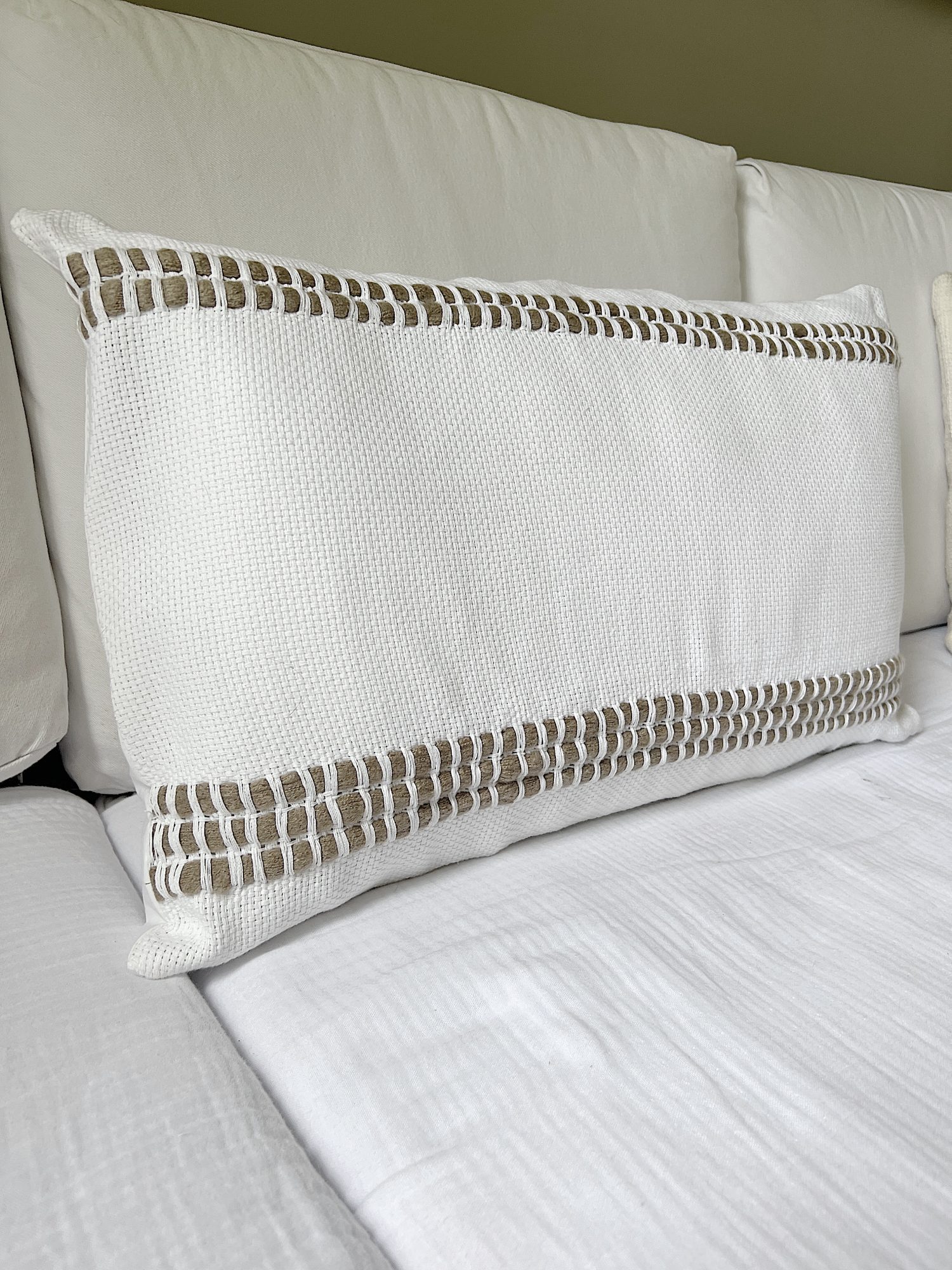 Handmade monk cloth pillow with yarn sitting on top of a couch.