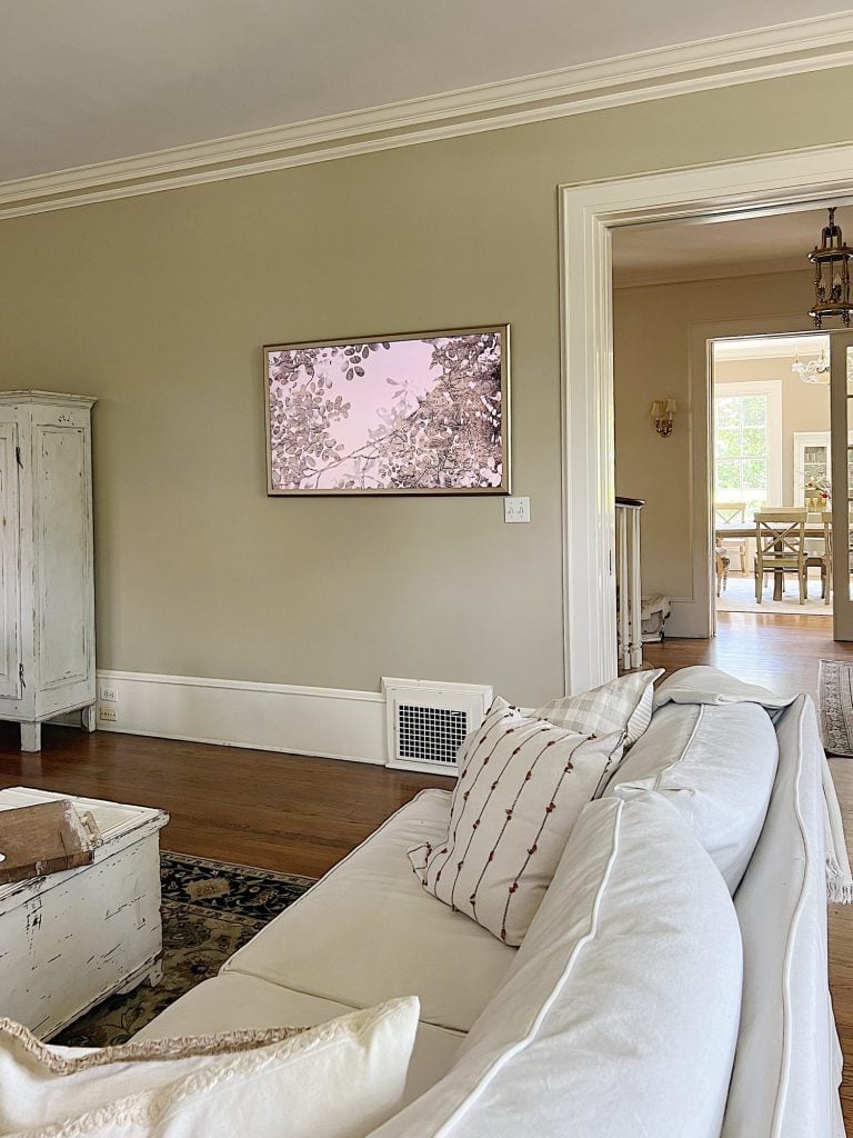 A frame TV on the wall of a newly refreshed living room with light couches and accents.