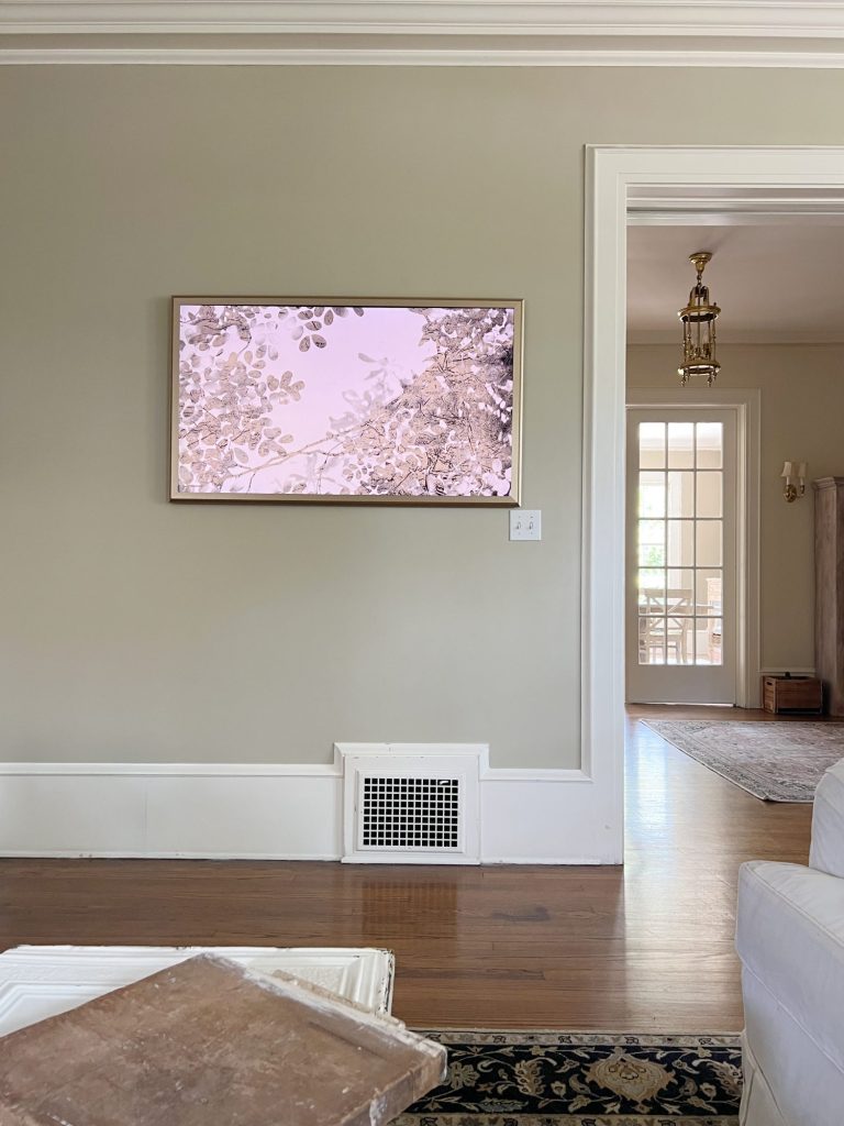 A frame TV on the wall of a newly refreshed living room with light couches and accents.