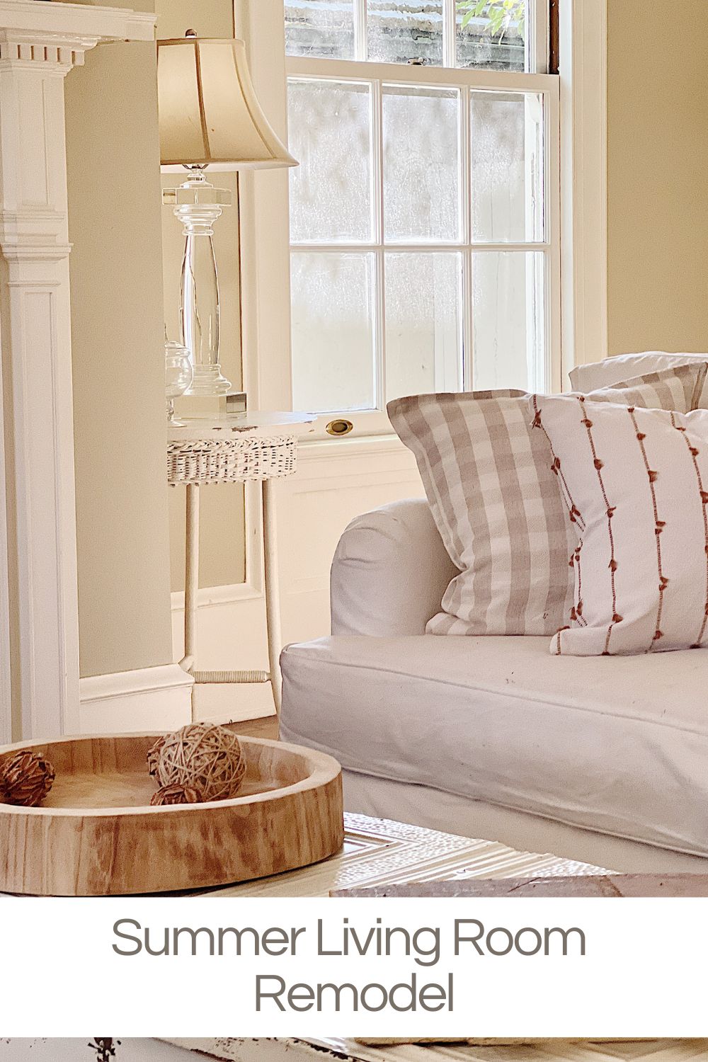 Summer living room remodel with a white couch, new print pillows, a modern lamp, and accessories on the coffee table.