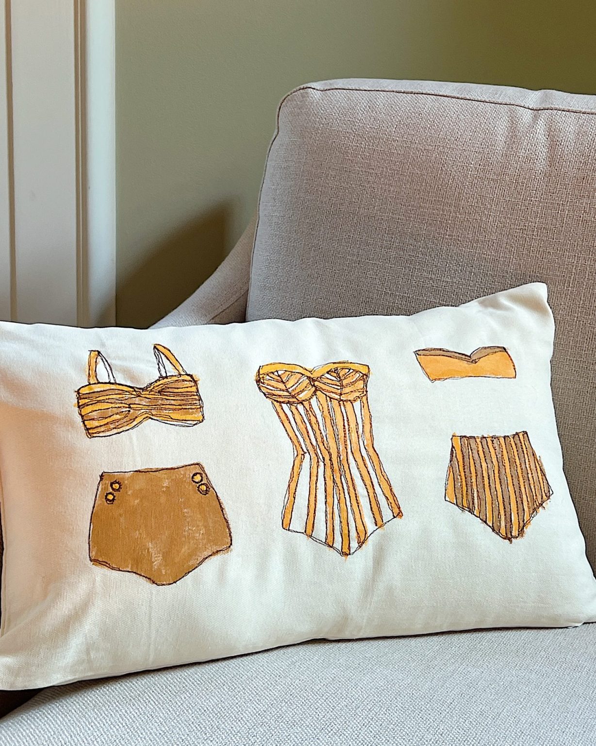 DIY pillow featuring painted and stitched vintage bathing suites in a modern coastal vintage style.
