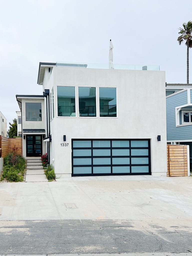 Our modern beach house in Ventura with white plaster finish, glass windows and a new garage door.