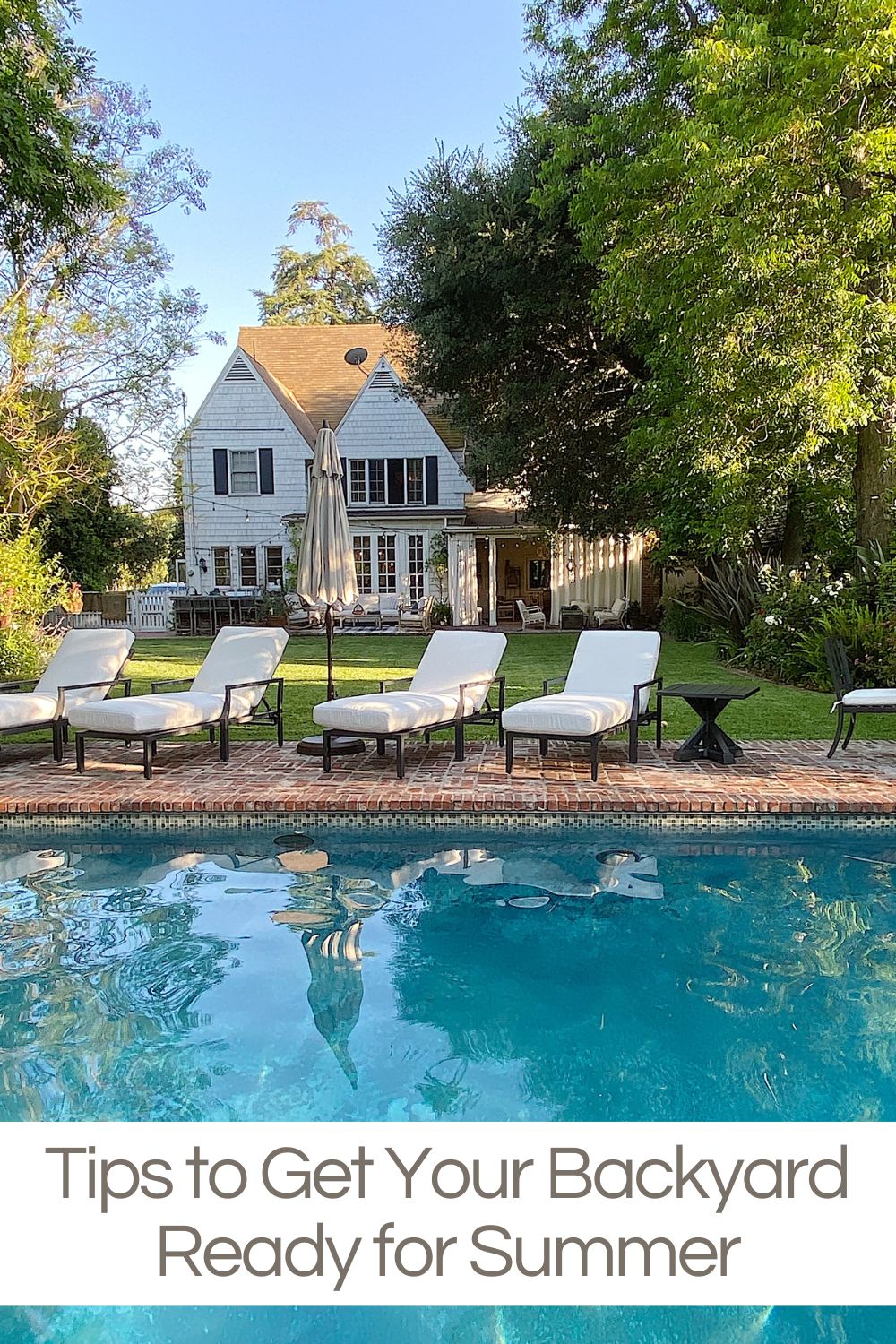 Our backyard with a one hundred year old home, a grass area, and a pool with patio furniture.