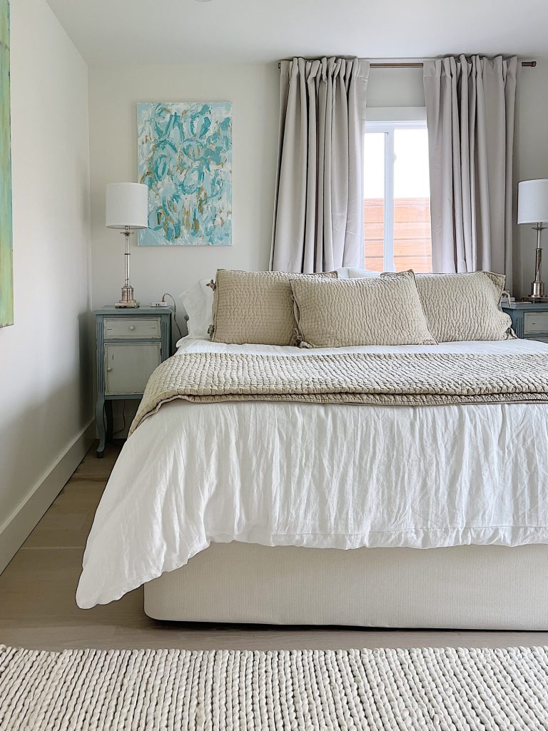 King bedded room at the beach house with white and tan bedding and a new white rug.
