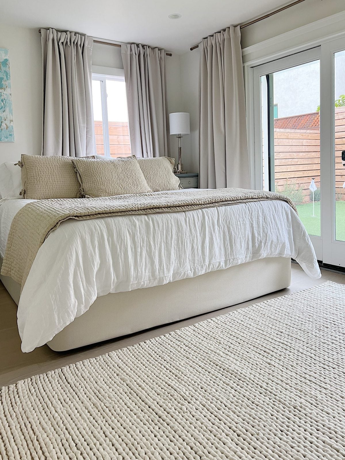 King bedded room at the beach house with white and tan bedding and a new white rug.