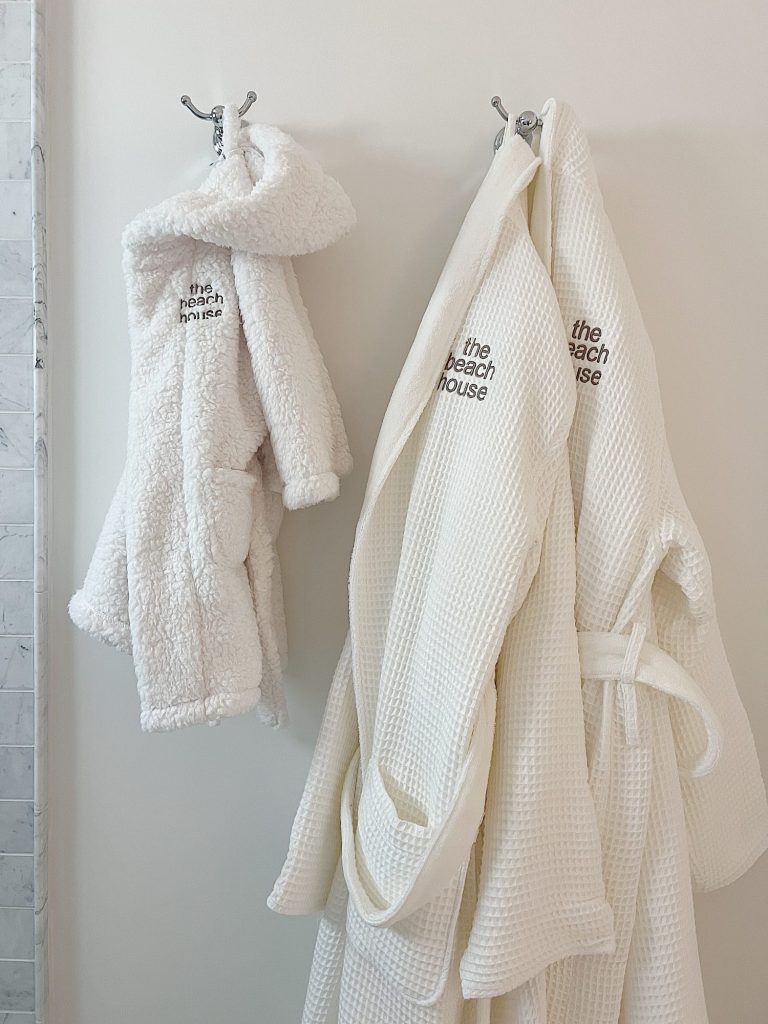 Embroidered robes hanging on hooks in a bathroom.