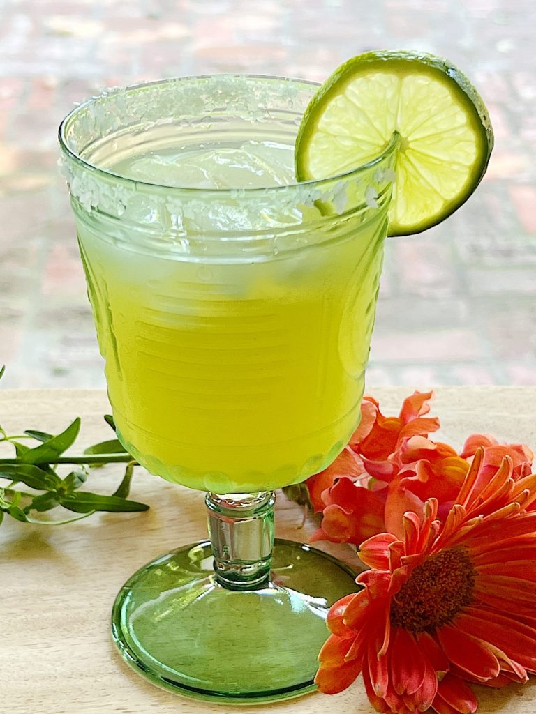 A freshly made Margarita Refreshing Summer Mocktail with a lime slice in a green glass.