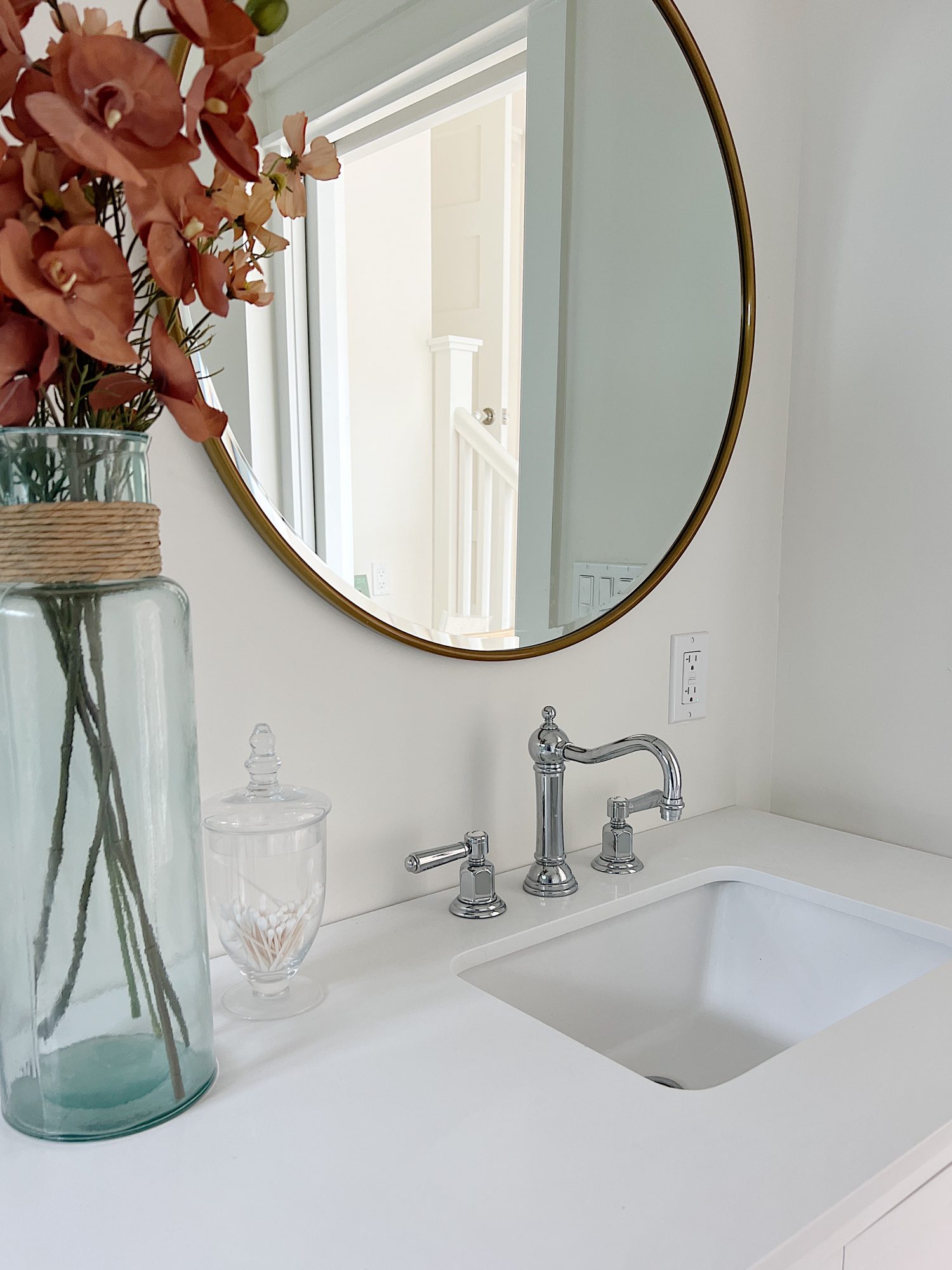 A newly constructed primary bathroom with a double sink vanity, marble tile shower, and decor.