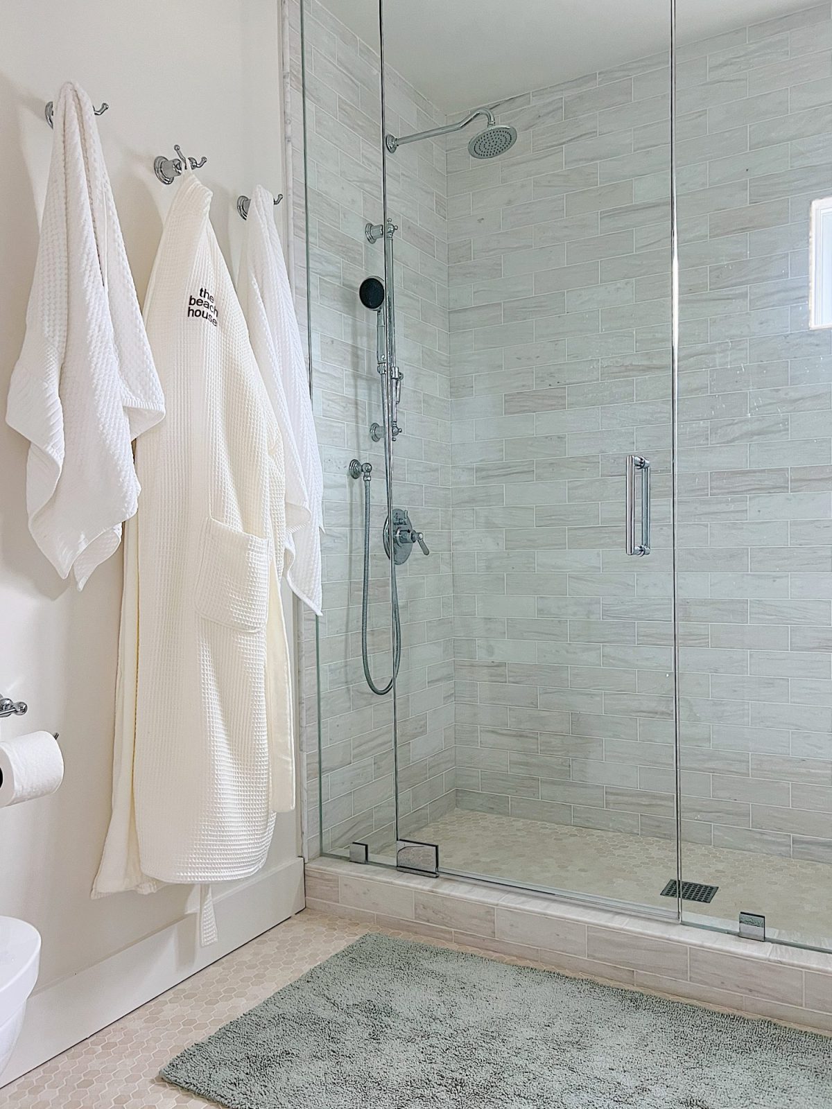Embroidered robes hanging on hooks in a bathroom.