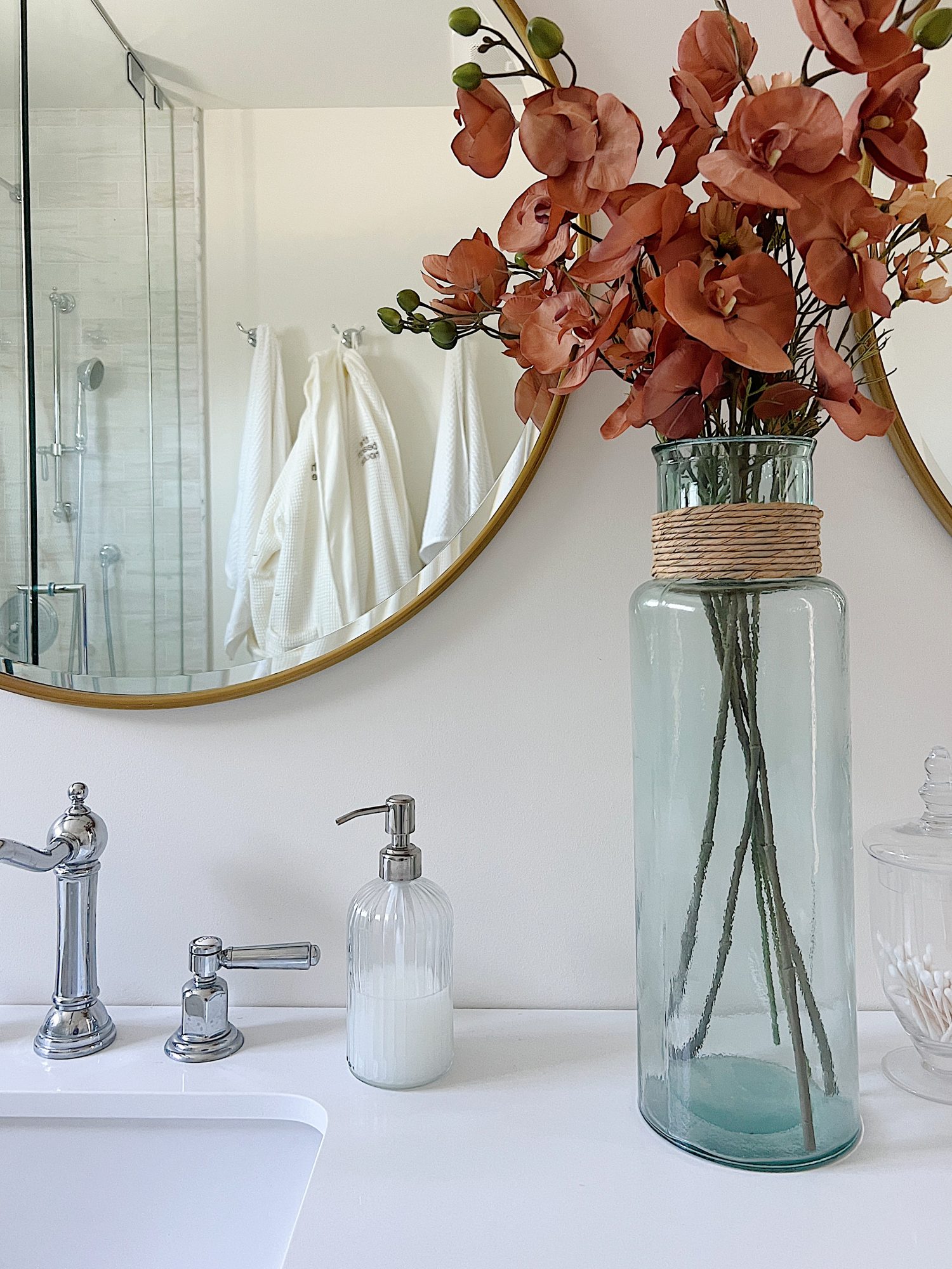 A newly constructed primary bathroom with a double sink vanity, marble tile shower, and decor.