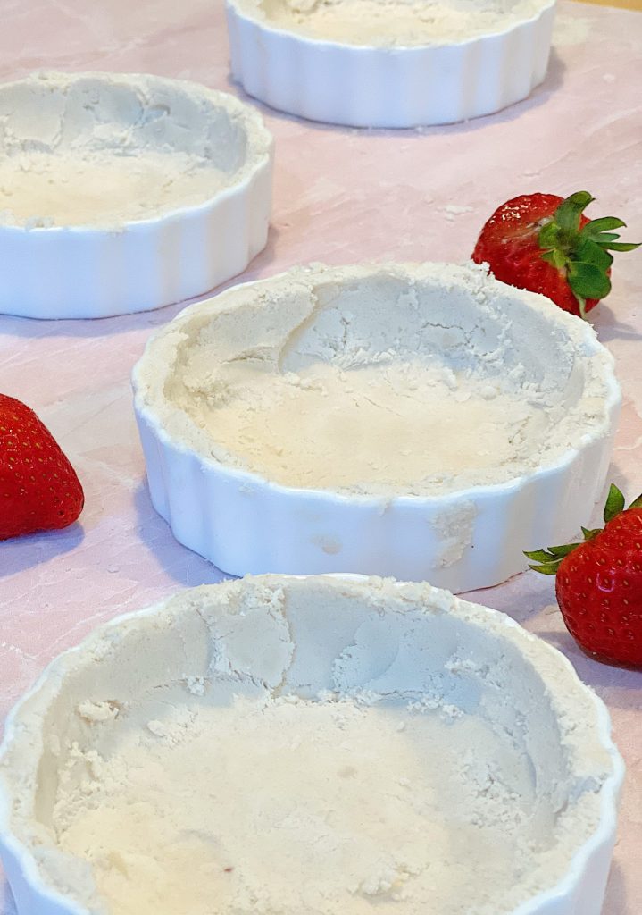 A mini white tart pan with fresh strawberries filled with a delicious tart crust.