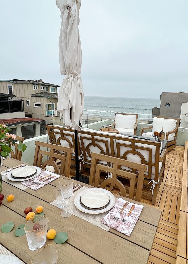 The deck on our third floor with Arhaus furniture, a fire pit, and dinner decor items.