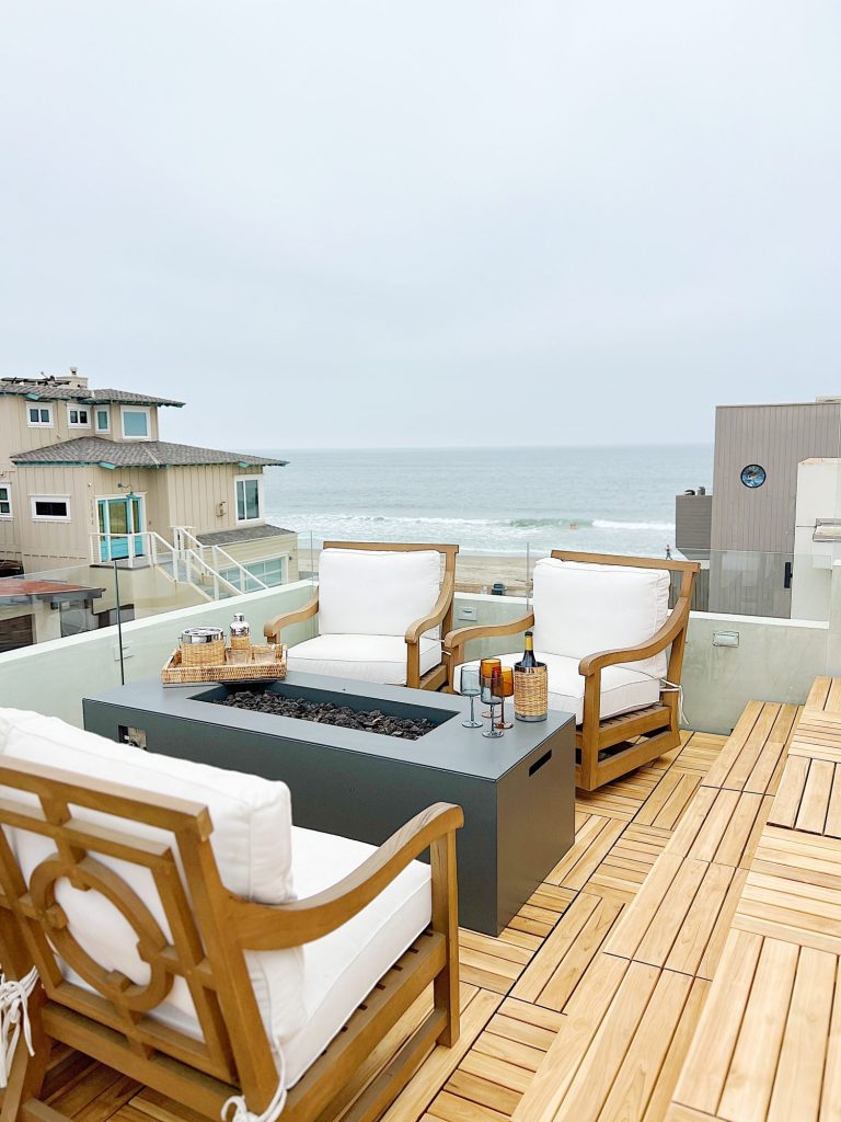 The deck on our third floor with Arhaus furniture, a fire pit, and dinner decor items.