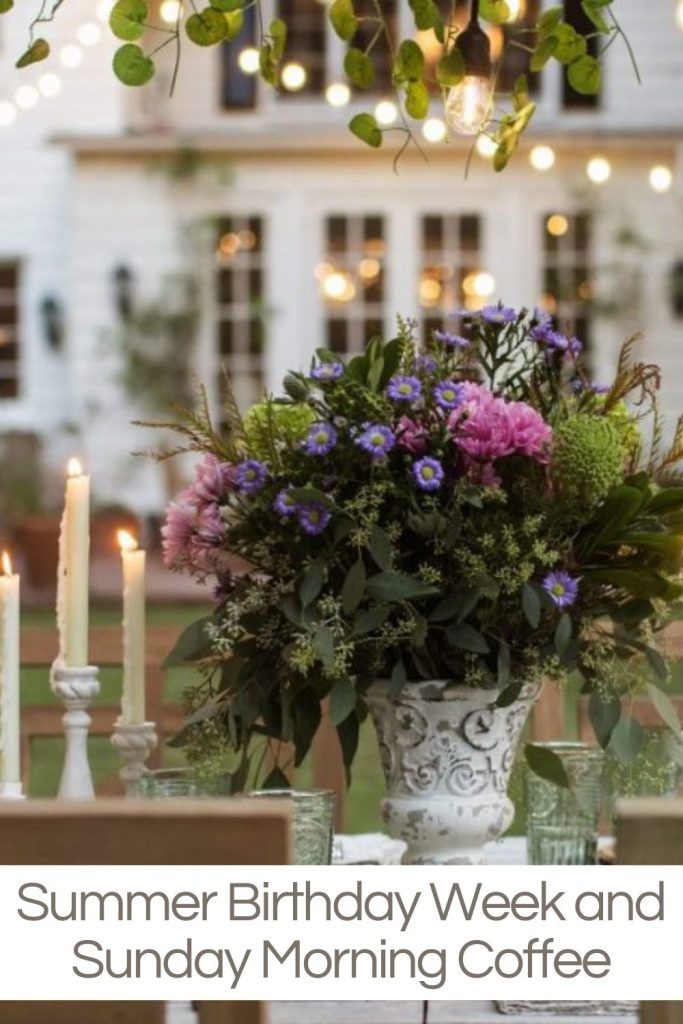 Table set in the backyard with a large fresh flower centerpiece and lights strung above.