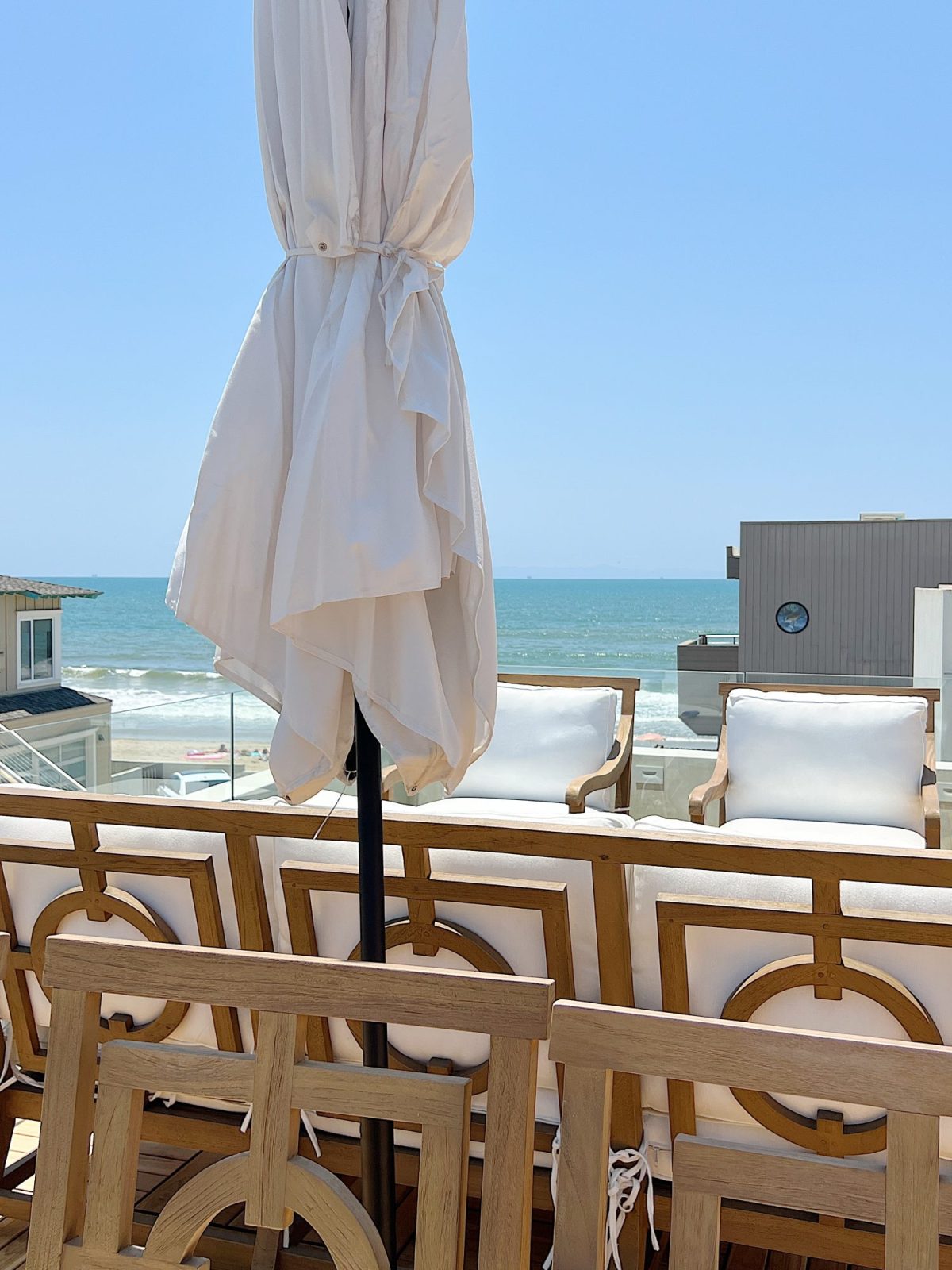 The Beach house deck with an ocean view and wood furniture.