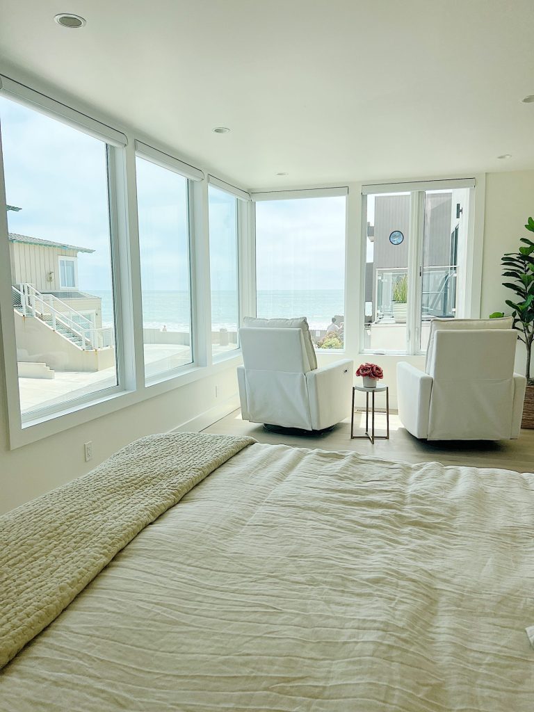 The primary bedroom in our beach house with five windows and an ocean view.