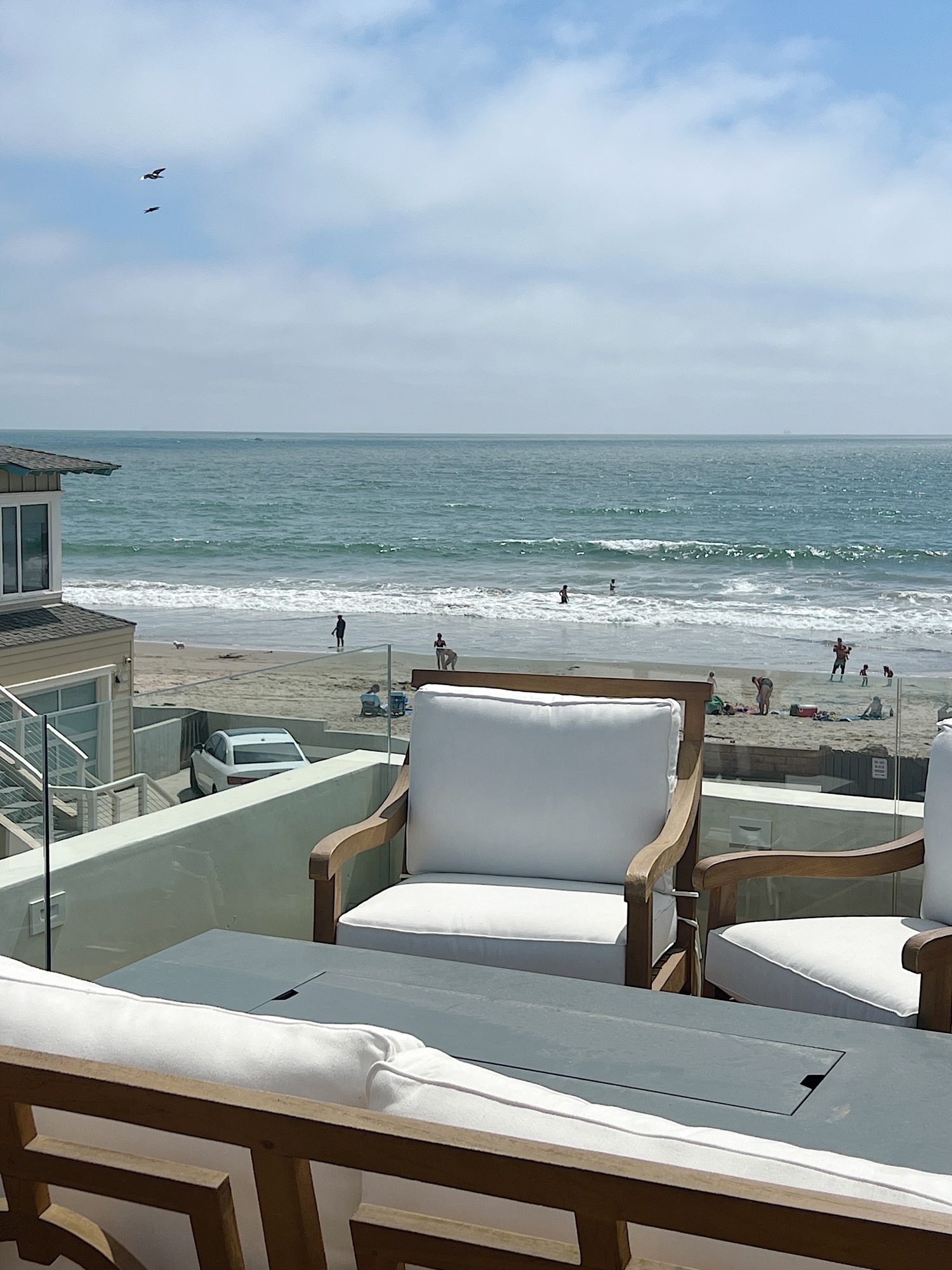 beach deck with two swivel chairs and a fire pit with the beach in the back ground.