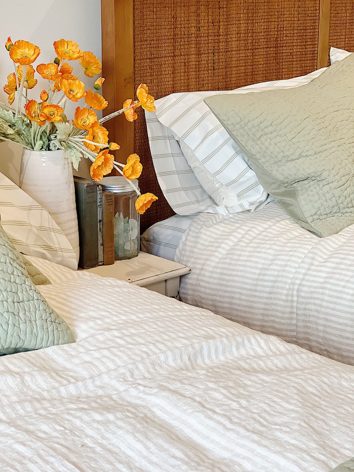 A bedroom at the beach house with two queen beds with sage green and cream bedding.