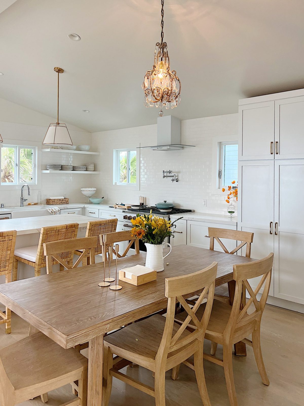 The finished beach house kitchen with white cabinets, countertops, appliances, a wood table, and an island.
