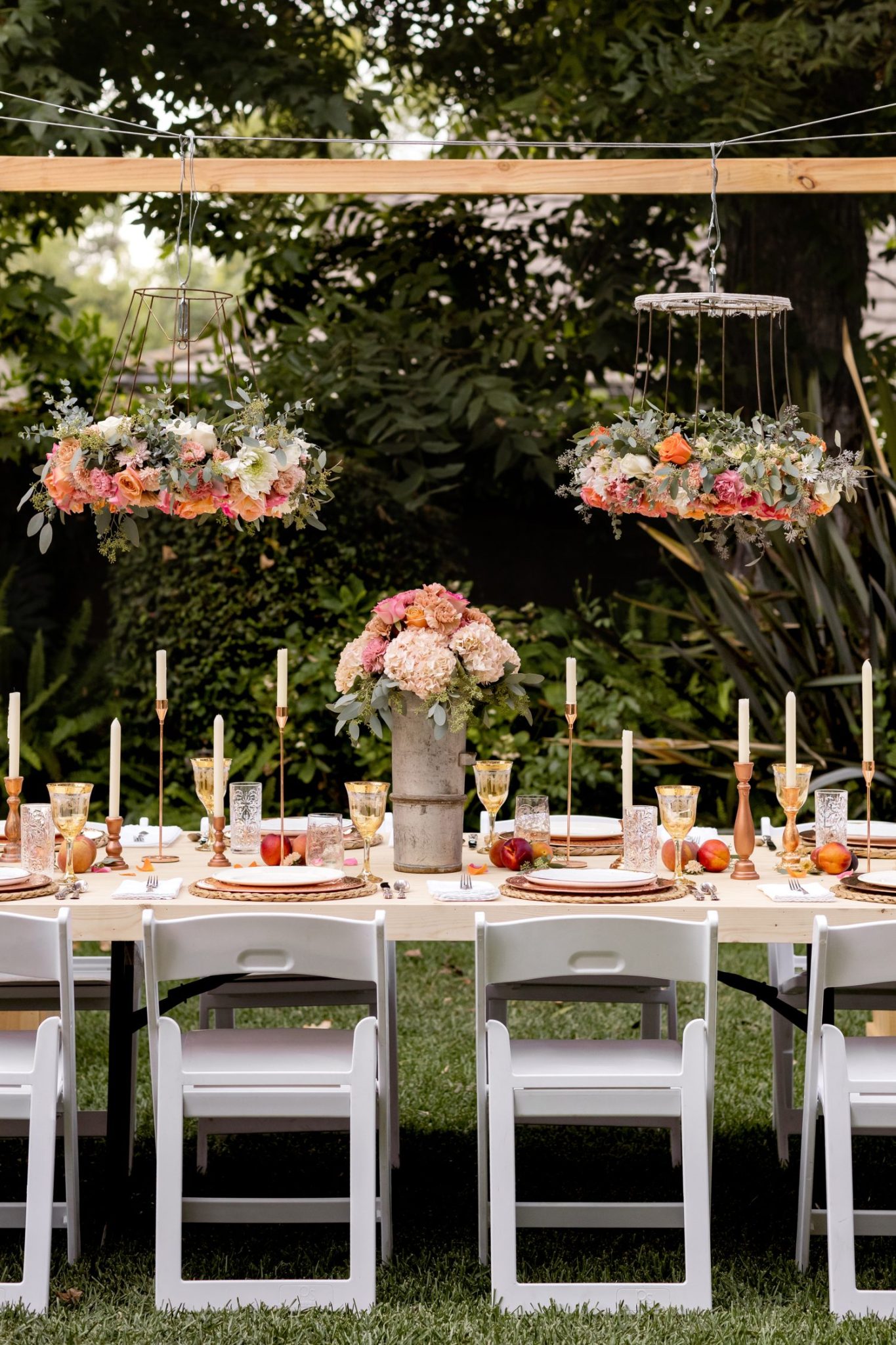 A handmade flower crown made from a vintage lampshade, oasis, and fresh flowers hanging on top of a magical table set for 40 guests.